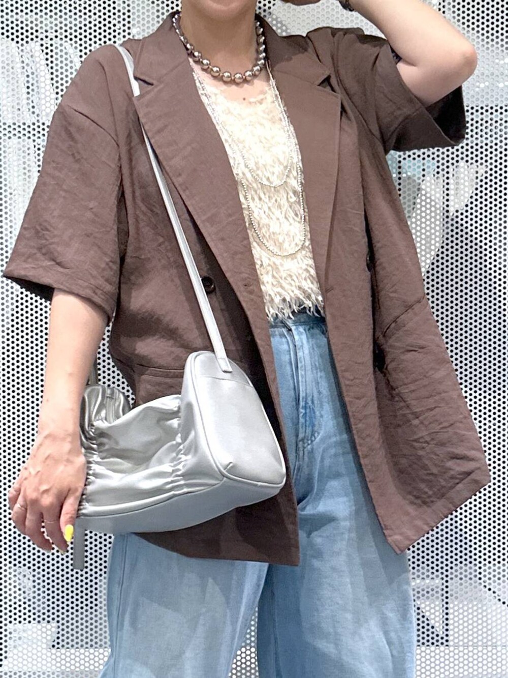 ブルー系のデニムパンツ、シルバー系のショルダーバッグ、ホワイト系のベストを着用したレディースの夏コーディネートの4枚目の写真