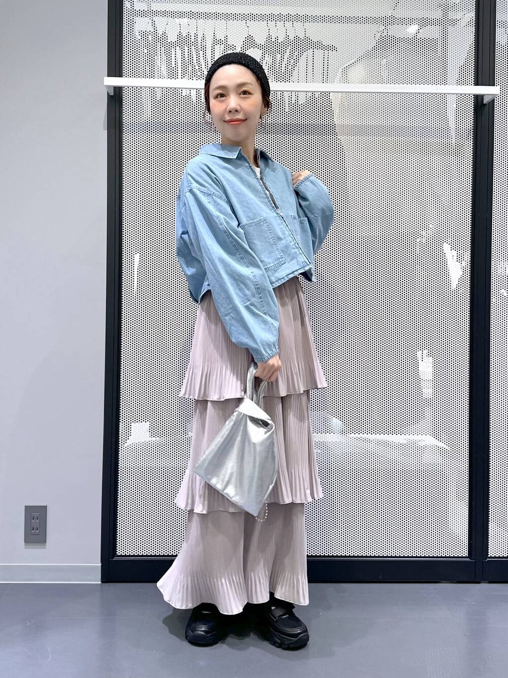 ブラック系のスニーカー、ブルー系のデニムジャケット、シルバー系のショルダーバッグを着用したレディースの春コーディネートの2枚目の写真