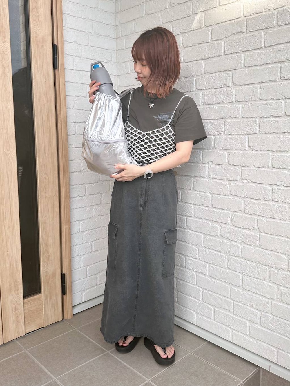 グレー系のデニムスカート、シルバー系のバックパック/リュック、ブラック系のサンダルを着用したレディースの春コーディネートの4枚目の写真