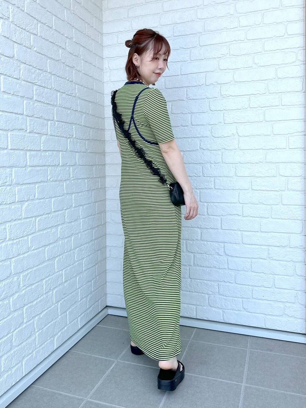 グリーン系のワンピース、ブラック系のサンダル、ブラック系のポーチを着用したレディースの春コーディネートの3枚目の写真