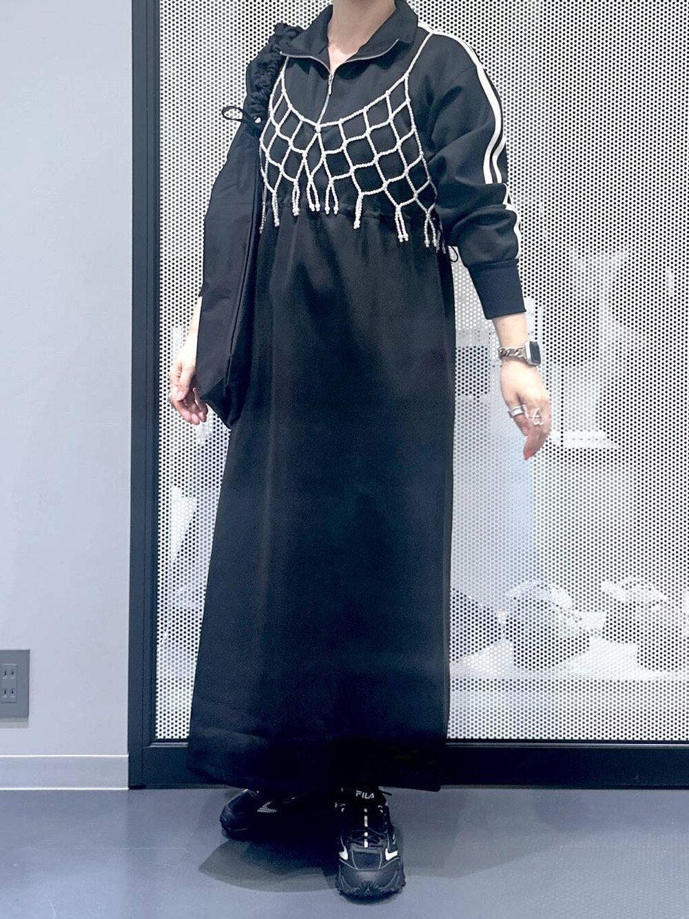 グレー系のスニーカー、ホワイト系のベスト、ブラック系のショルダーバッグを着用したレディースの秋コーディネートの5枚目の写真