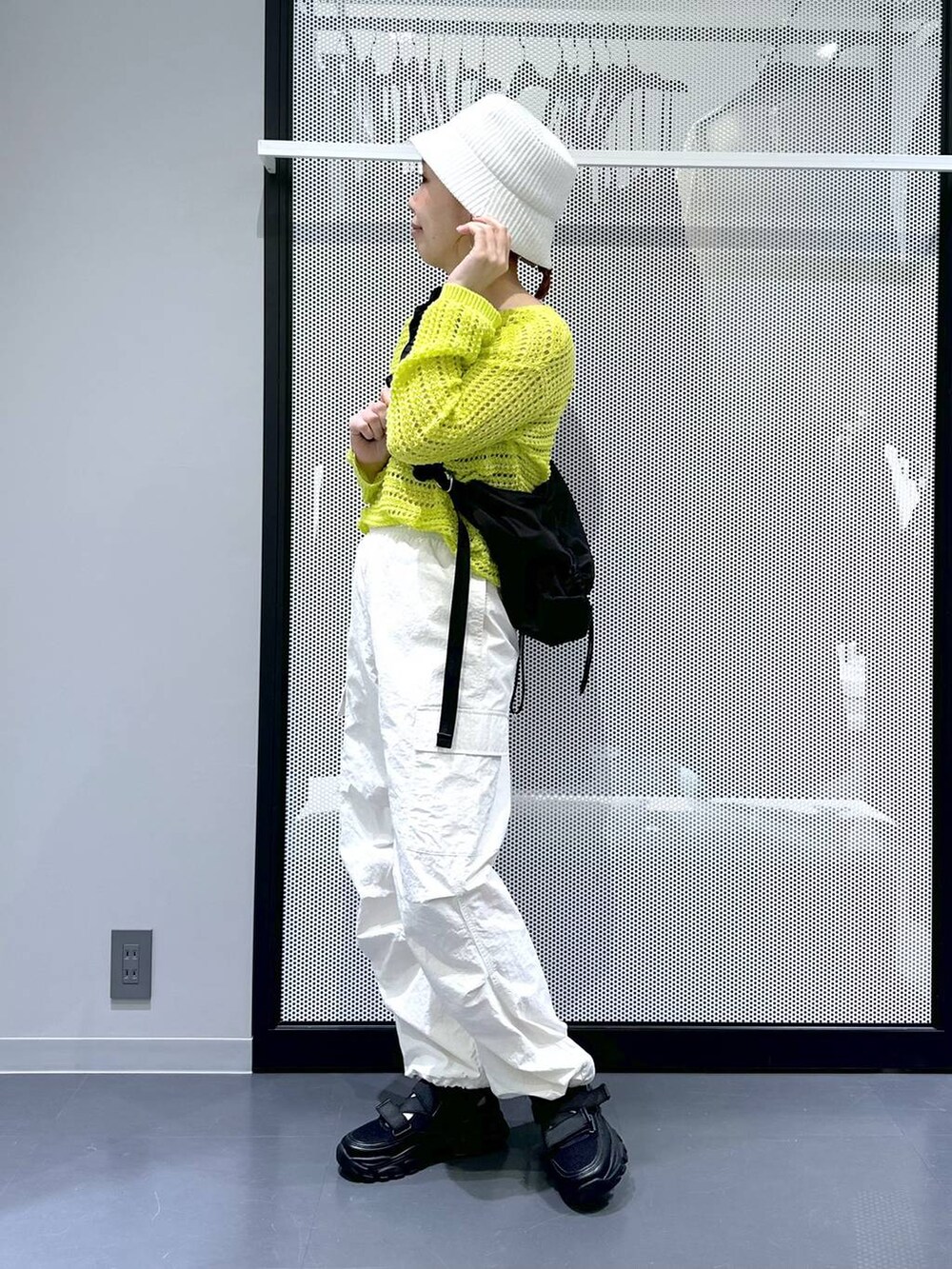 ブラック系のスニーカー、ホワイト系のカーゴパンツ、グリーン系のニット/セーターを着用したレディースの春コーディネートの2枚目の写真