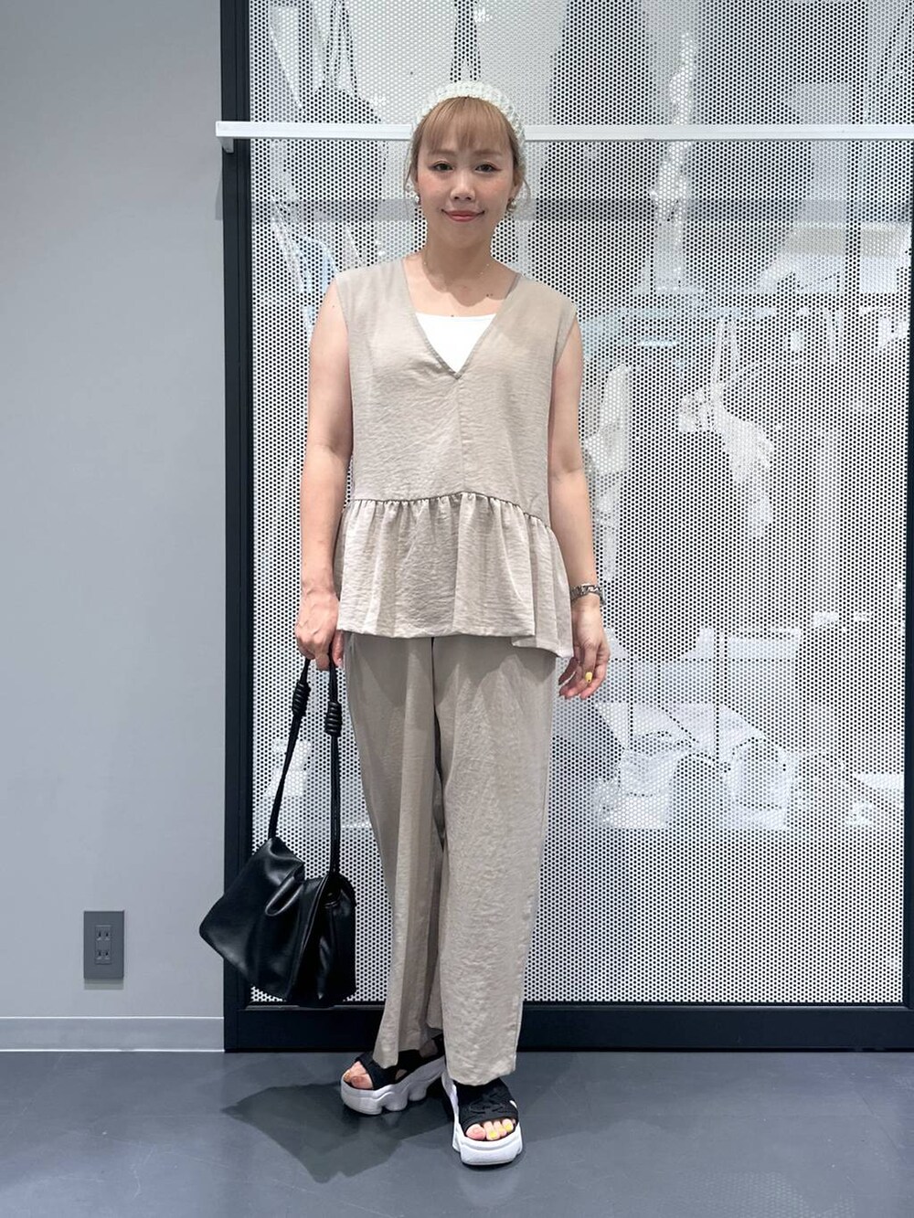 ブラック系のショルダーバッグ、ベージュ系のその他パンツ、ベージュ系のベストを着用したレディースの夏コーディネートの2枚目の写真