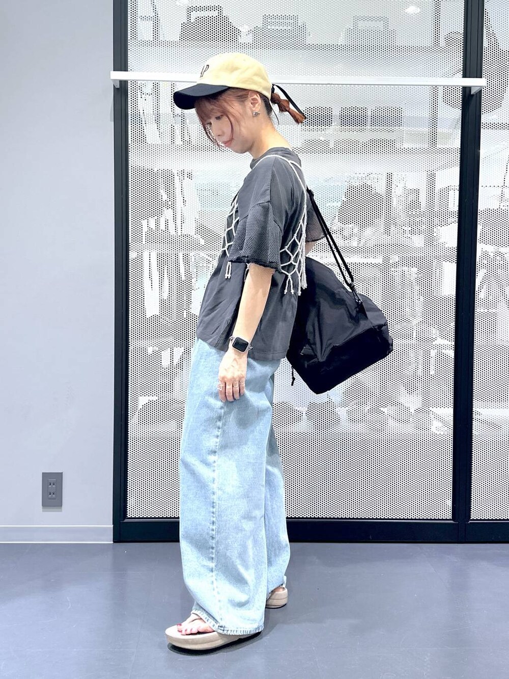 ブラック系のショルダーバッグ、ブルー系のデニムパンツ、ホワイト系のベストを着用したレディースの夏コーディネートの3枚目の写真