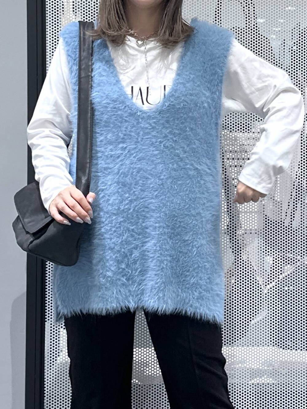 ブラック系のショルダーバッグ、ブルー系のベスト、ホワイト系のTシャツ/カットソーを着用したレディースの秋コーディネートの4枚目の写真
