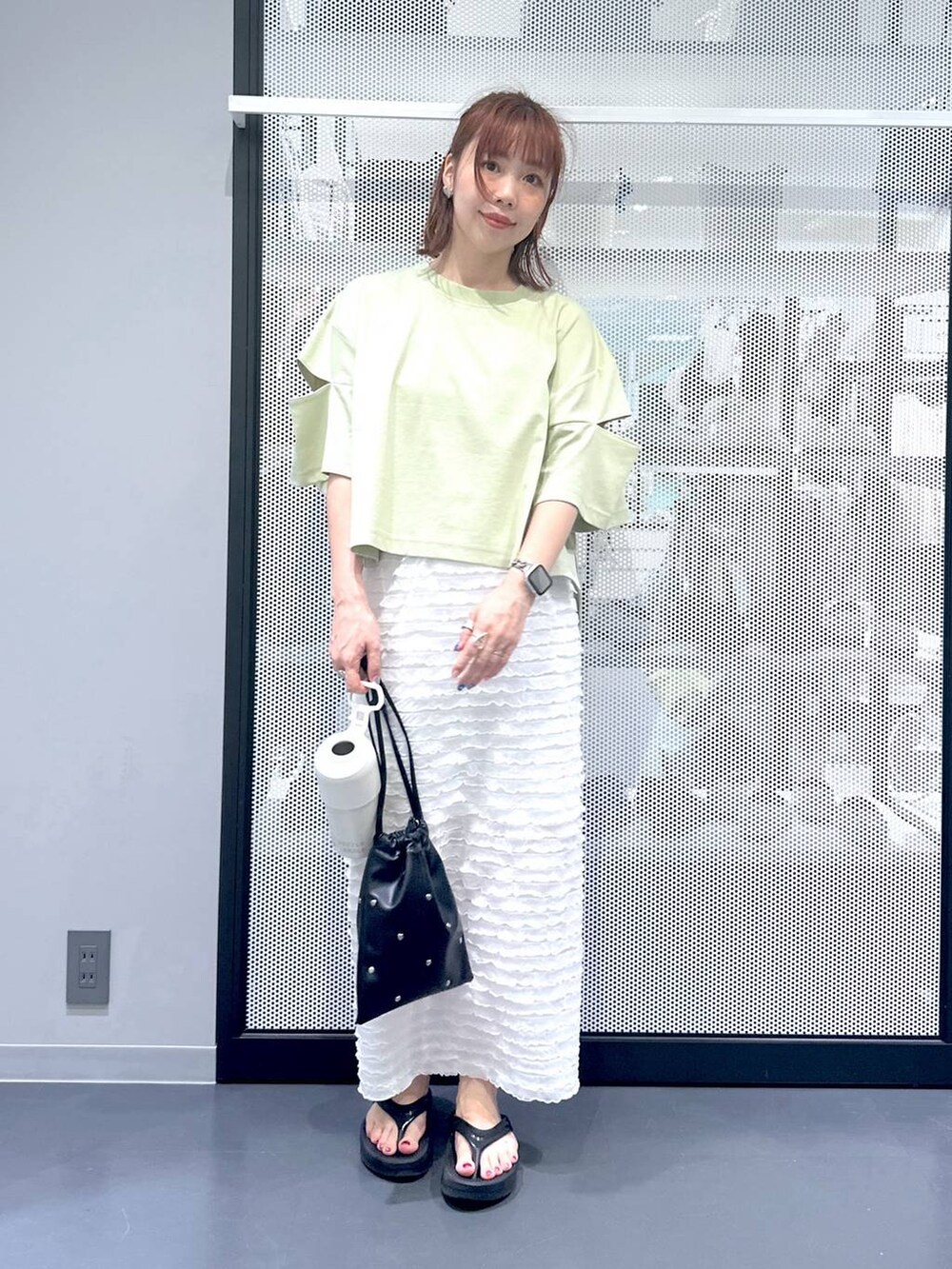 ブラック系のショルダーバッグ、ホワイト系のスカート、グリーン系のTシャツ/カットソーを着用したレディースの夏コーディネートの4枚目の写真