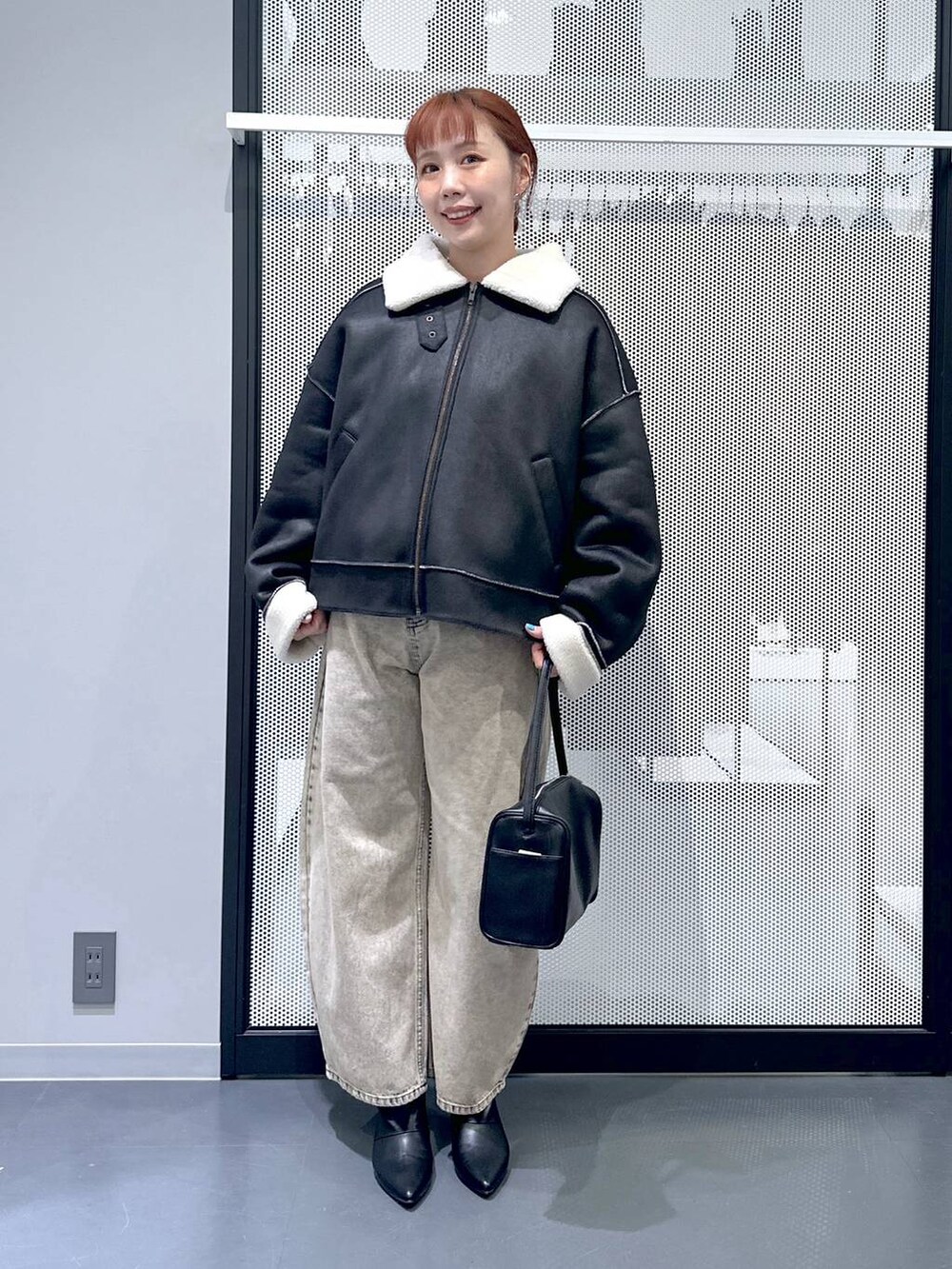 ブラック系のショルダーバッグ、ブラック系のブルゾン、ベージュ系のデニムパンツを着用したレディースの秋コーディネートの6枚目の写真