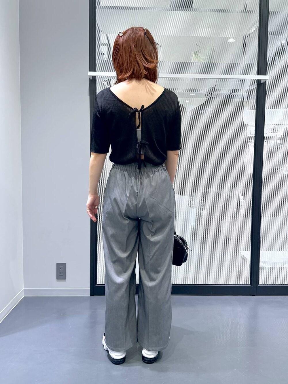 ブラック系のショルダーバッグ、ブラック系のカーディガン/ボレロ、グレー系のスラックスを着用したレディースの夏コーディネートの4枚目の写真