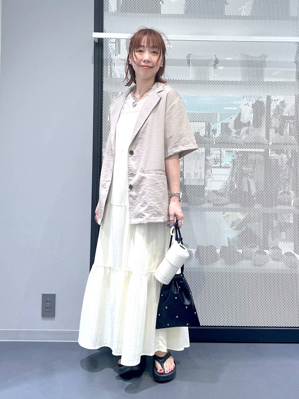 ブラック系のショルダーバッグ、ベージュ系のワンピース、ベージュ系のTシャツ/カットソーを着用したレディースの夏コーディネートの3枚目の写真