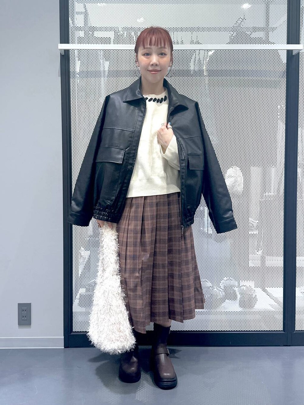 ホワイト系のショルダーバッグ、ブラック系のブルゾン、ブラウン系のブーツを着用したレディースの秋コーディネートの2枚目の写真