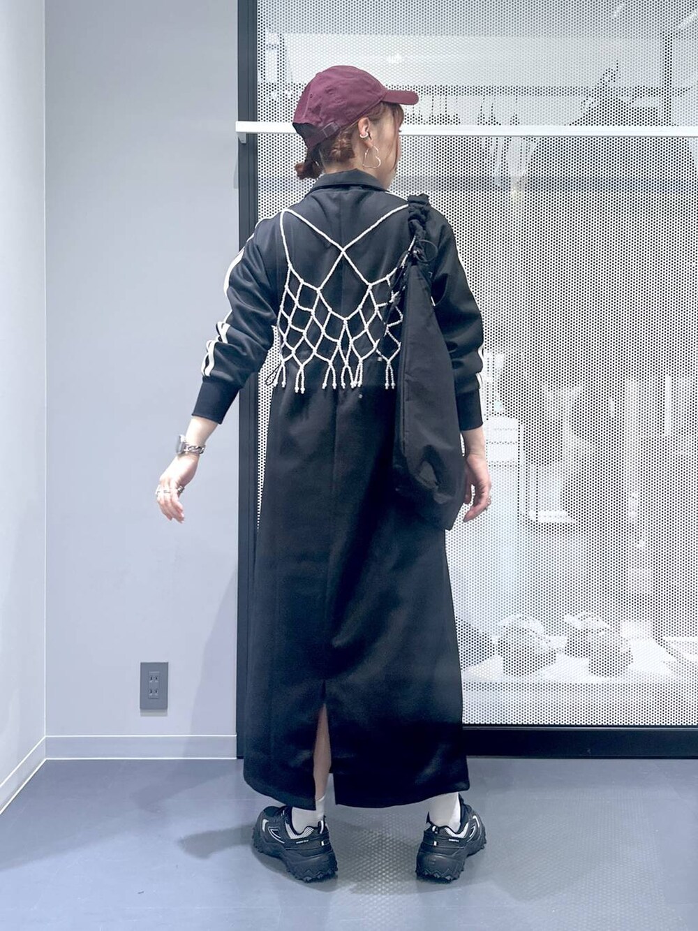 グレー系のスニーカー、ホワイト系のベスト、ブラック系のショルダーバッグを着用したレディースの秋コーディネートの4枚目の写真