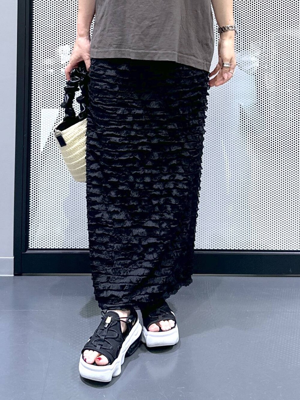 グレー系のTシャツ/カットソー、ブラック系のスカート、ホワイト系のショルダーバッグを着用したレディースの夏コーディネートの6枚目の写真