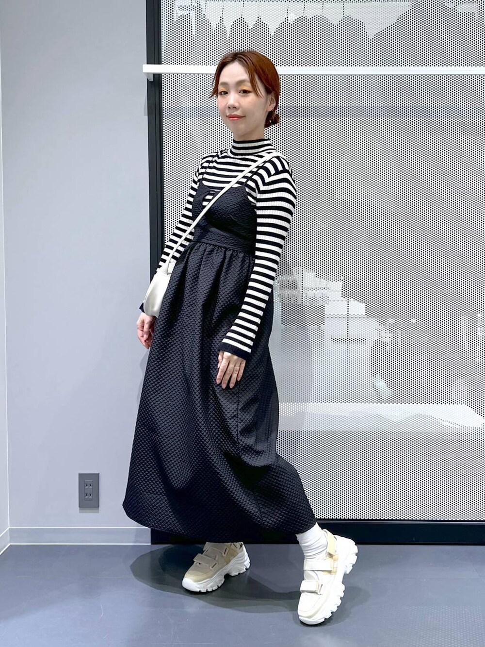 ベージュ系のスニーカー、ブラック系のワンピース、ホワイト系のショルダーバッグを着用したレディースの冬コーディネートの5枚目の写真