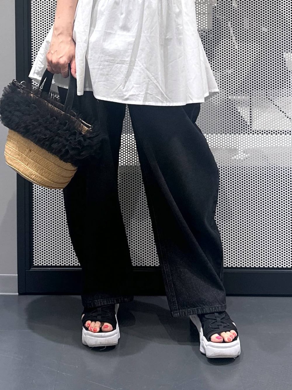 ブラック系のデニムパンツ、ベージュ系のショルダーバッグ、ホワイト系のタンクトップを着用したレディースの夏コーディネートの4枚目の写真