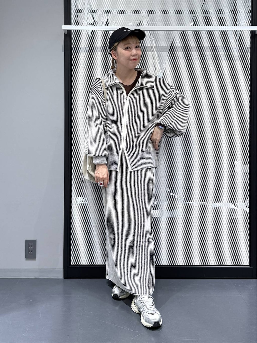 ベージュ系のトートバッグ、ベージュ系のスカート、ベージュ系のニット/セーターを着用したレディースの秋コーディネートの2枚目の写真