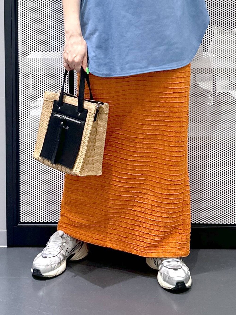 ベージュ系のショルダーバッグ、オレンジ系のスカート、ブルー系のTシャツ/カットソーを着用したレディースの春コーディネートの5枚目の写真