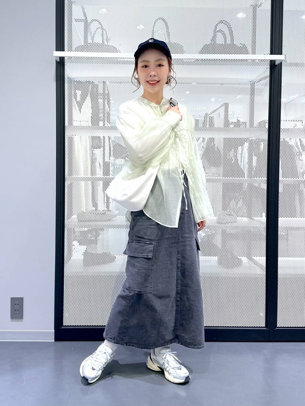 グレー系のデニムスカート、ホワイト系のTシャツ/カットソー、ホワイト系のショルダーバッグを着用したレディースの春コーディネートの5枚目の写真