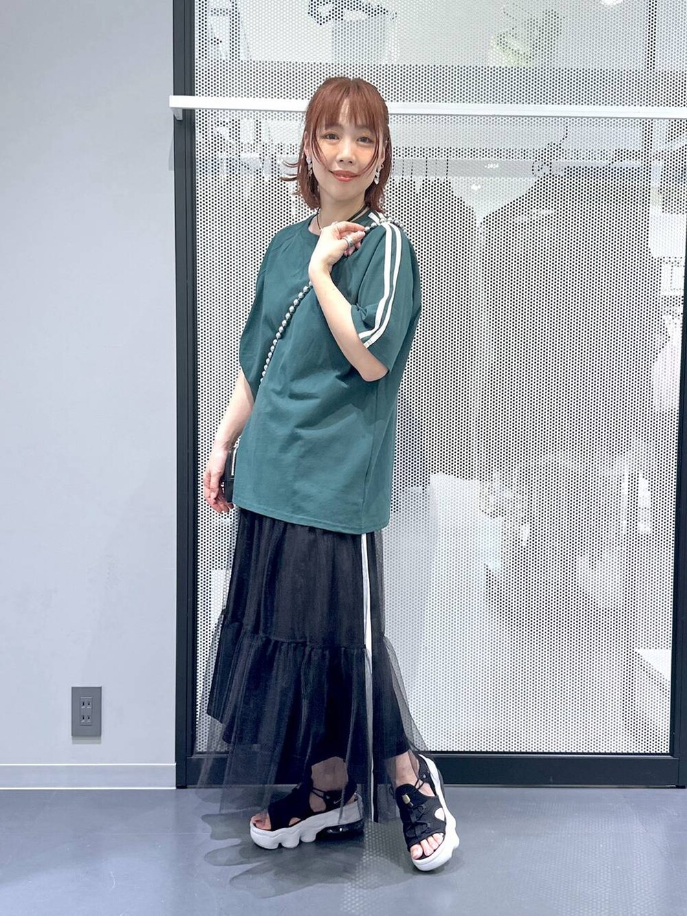 ブラック系のスカート、グリーン系のTシャツ/カットソー、その他のネックレスを着用したレディースの夏コーディネートの2枚目の写真