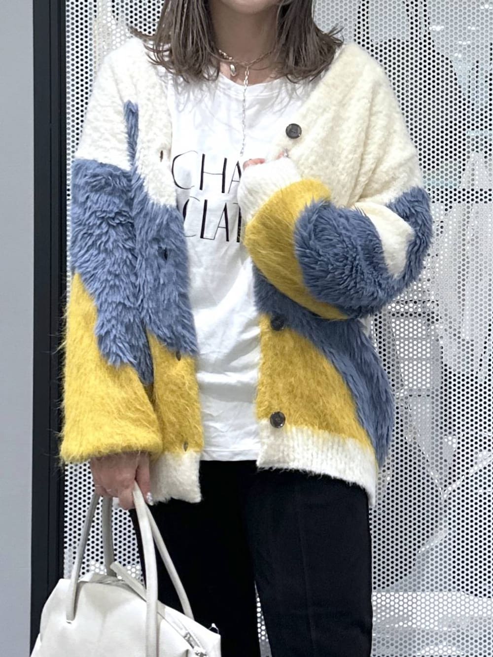 グレー系のボストンバッグ、イエロー系のカーディガン/ボレロ、ホワイト系のTシャツ/カットソーを着用したレディースの秋コーディネートの4枚目の写真