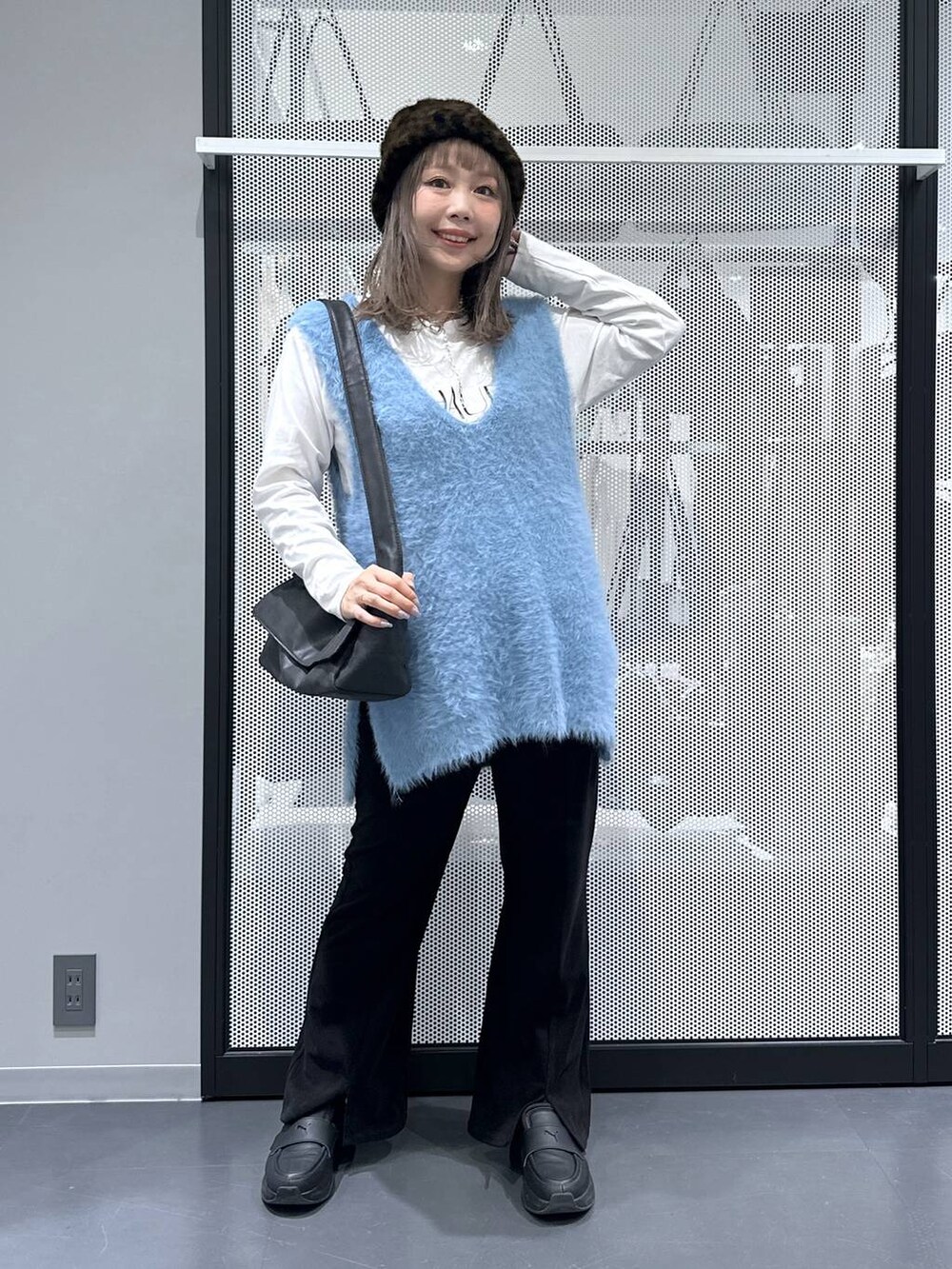 ブラック系のショルダーバッグ、ブルー系のベスト、ホワイト系のTシャツ/カットソーを着用したレディースの秋コーディネートの6枚目の写真