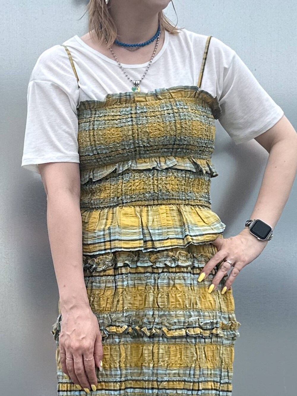 イエロー系のキャミソール、イエロー系のスカート、シルバー系のデジタル腕時計を着用したレディースの夏コーディネートの3枚目の写真