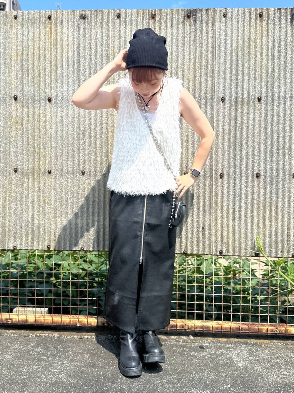 ブラック系のスカート、ブラック系のブーツ、ベージュ系のベストを着用したレディースの秋コーディネートの2枚目の写真