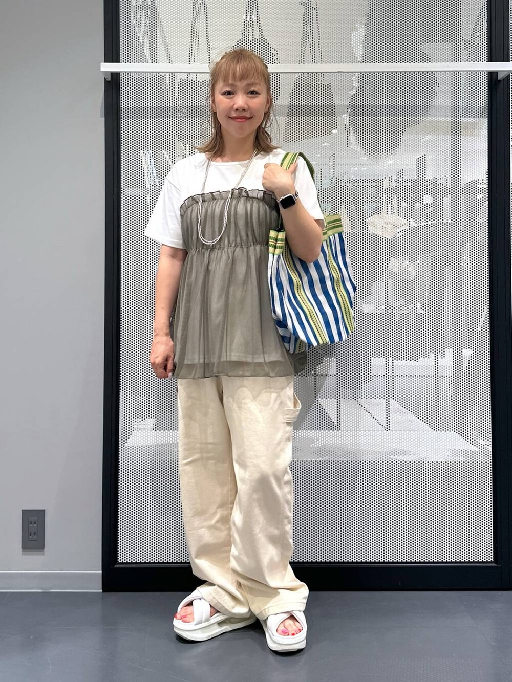 ブルー系のトートバッグ、グリーン系のTシャツ/カットソー、その他のピアス（両耳用）を着用したレディースの夏コーディネートの2枚目の写真