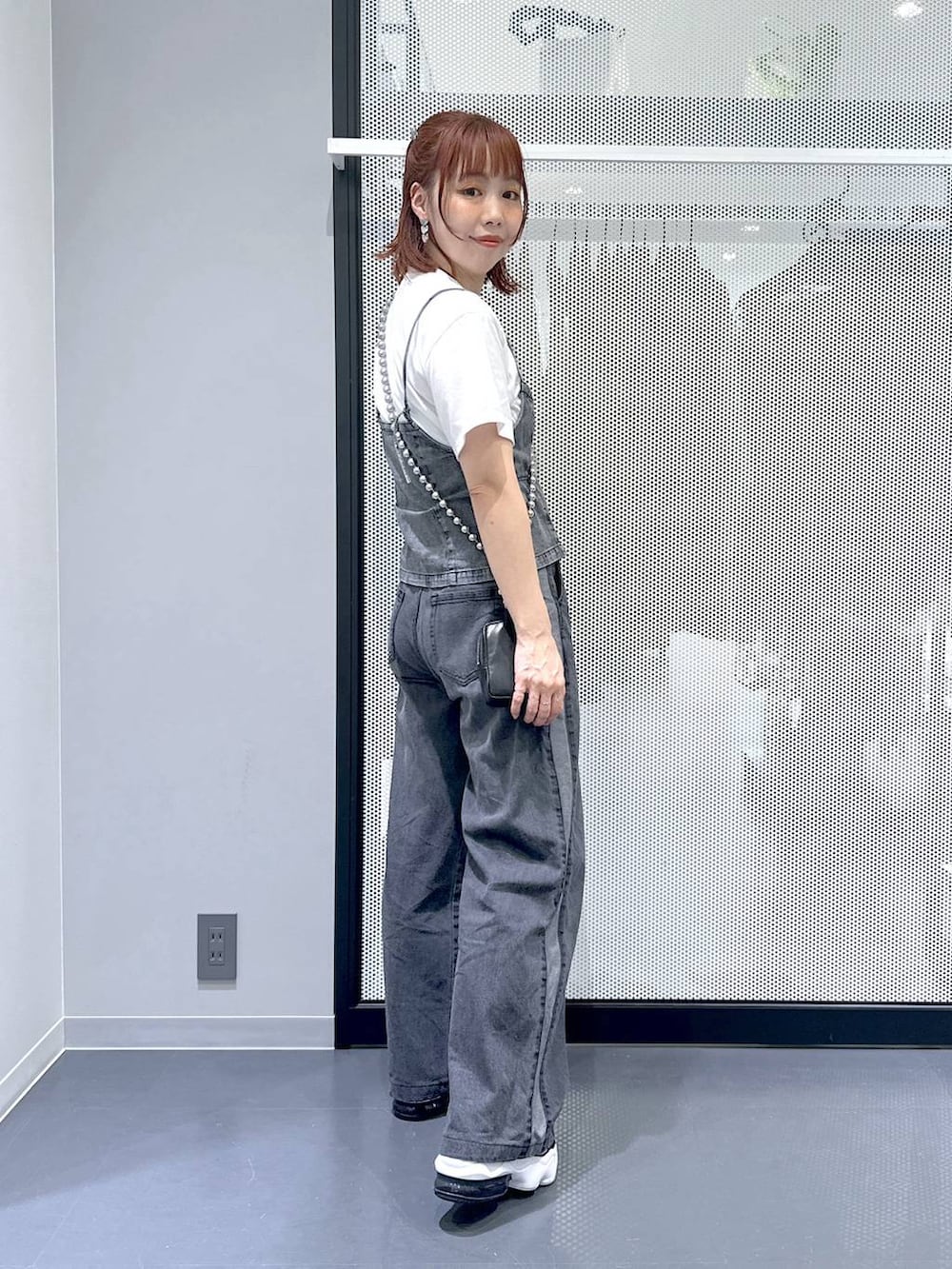 ブラック系のデニムパンツ、グレー系のベスト、ホワイト系のTシャツ/カットソーを着用したレディースの夏コーディネートの2枚目の写真