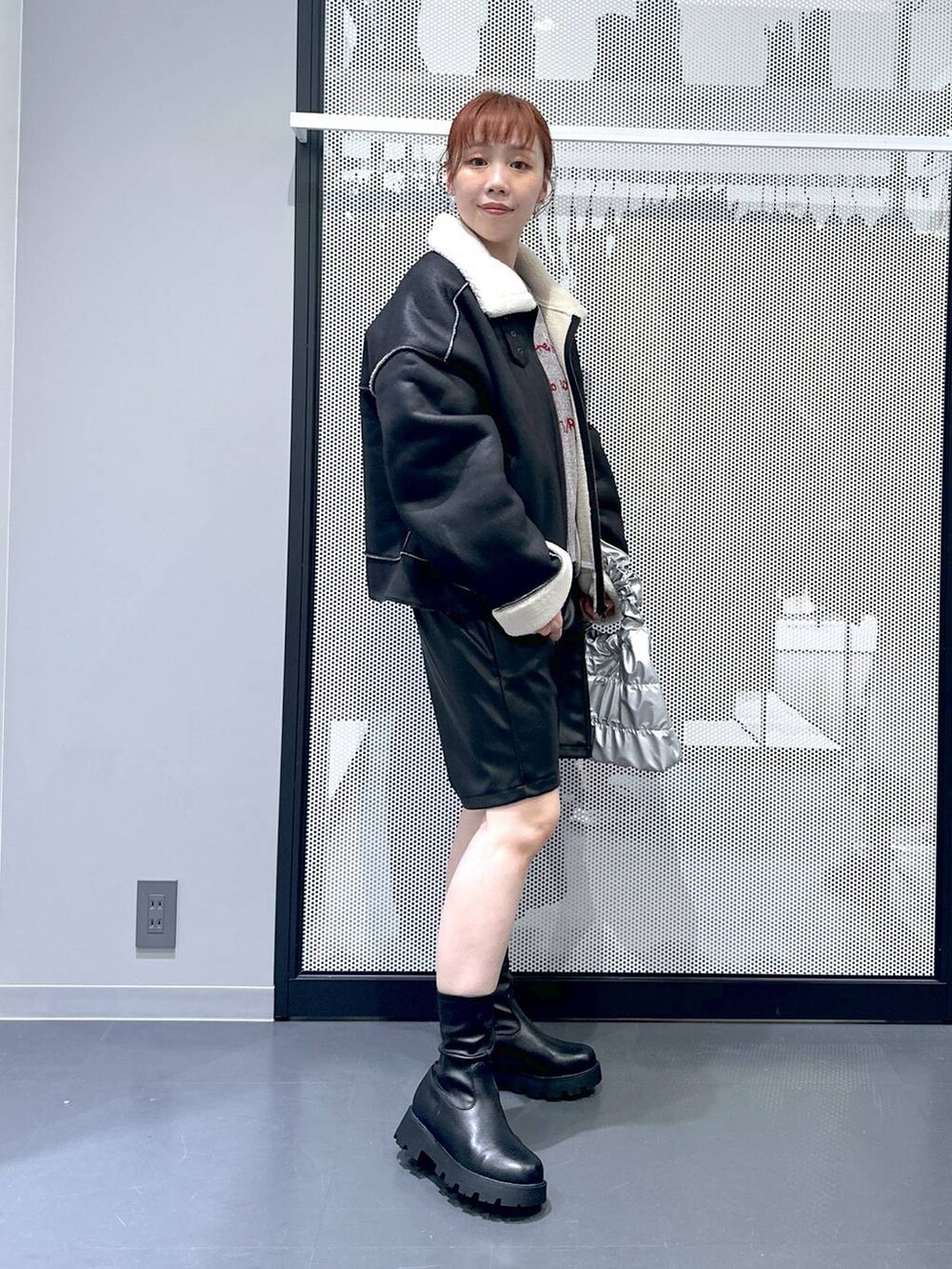 ブラック系のブルゾン、ブラック系のブーツ、シルバー系のショルダーバッグを着用したレディースの秋コーディネートの3枚目の写真