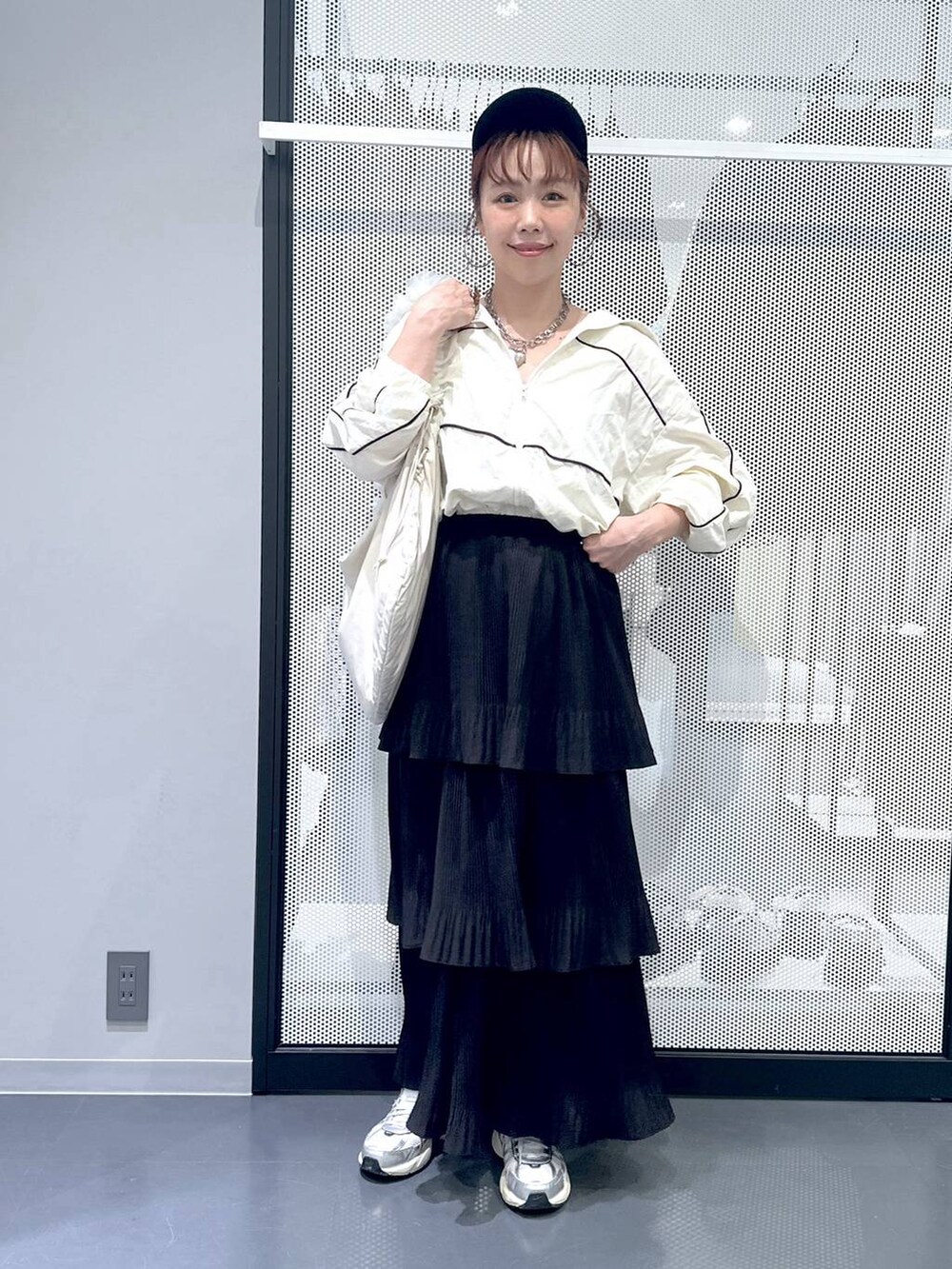 ブラック系のスカート、ホワイト系のショルダーバッグ、ベージュ系のブルゾンを着用したレディースの秋コーディネートの2枚目の写真