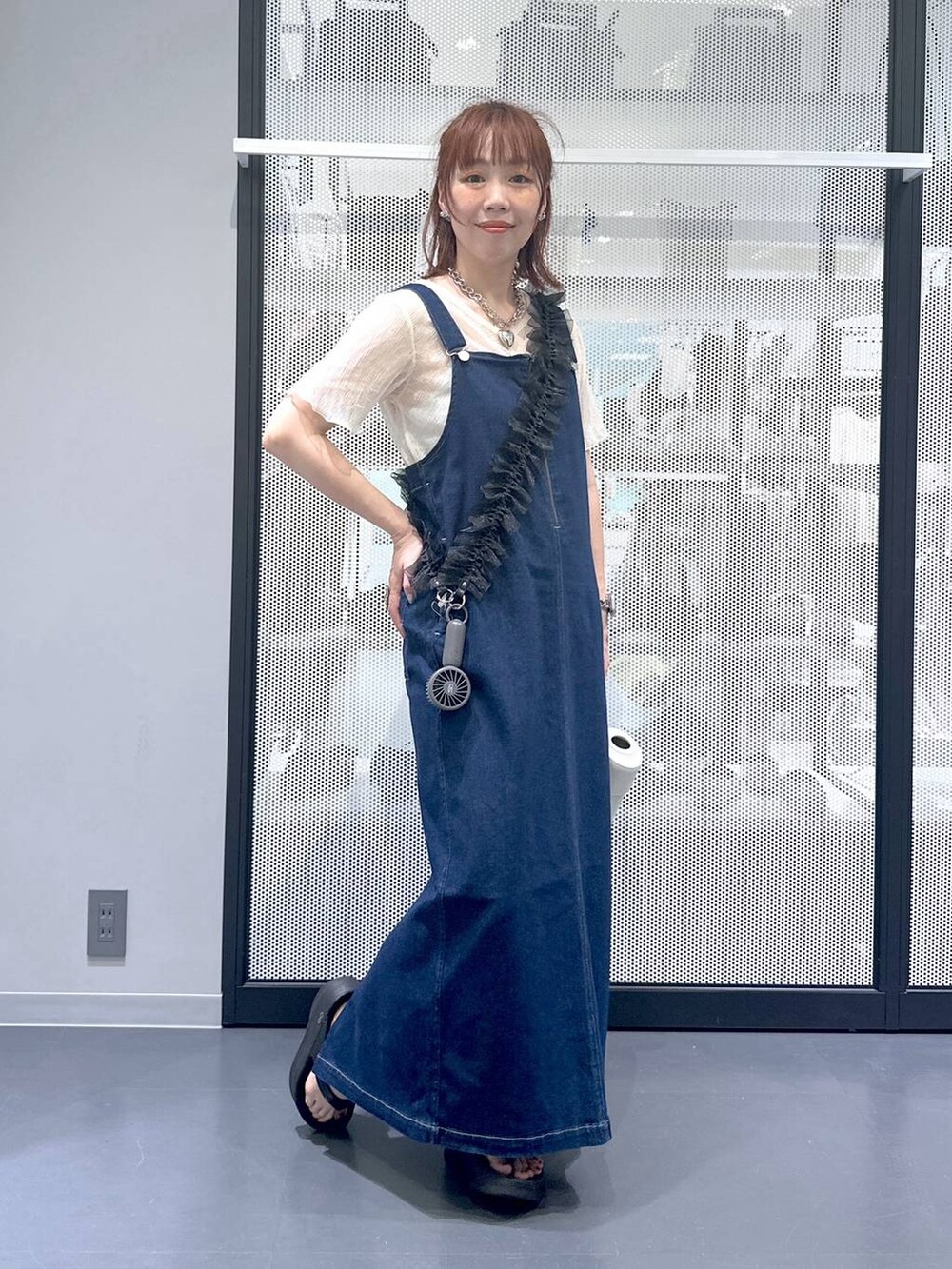ブルー系のジャンパースカート、ブラック系のサンダル、ベージュ系のTシャツ/カットソーを着用したレディースの夏コーディネートの5枚目の写真