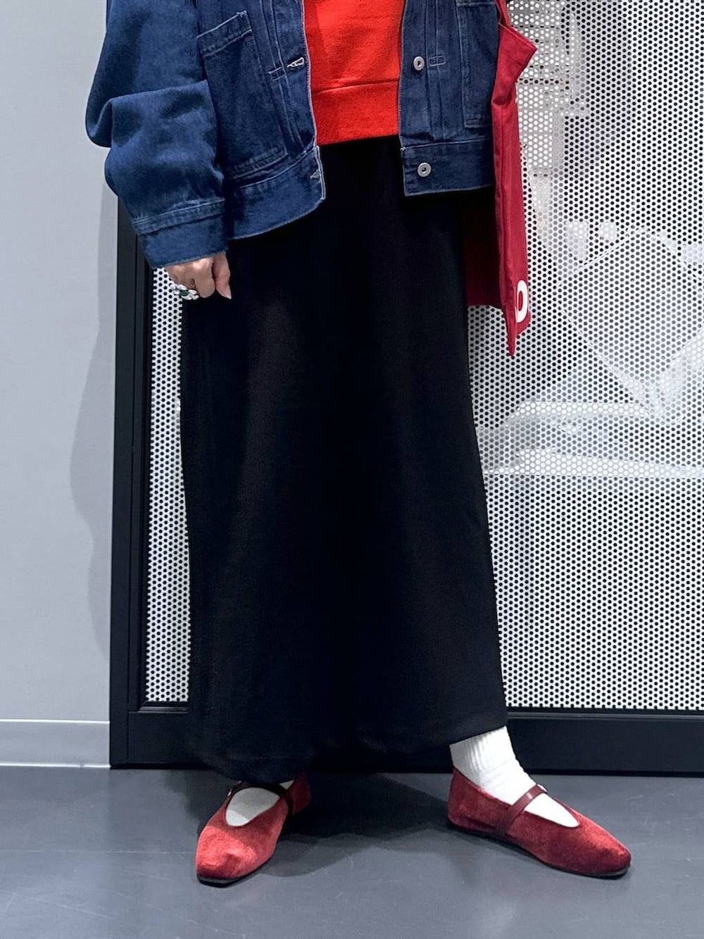 ブラック系のスカート、レッド系のトートバッグ、レッド系のパンプスを着用したレディースの秋コーディネートの5枚目の写真