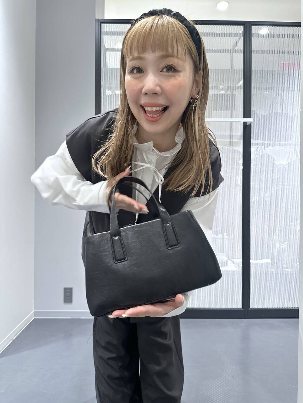 ブラック系のボストンバッグ、グレー系のスラックス、グレー系のベストを着用したレディースの冬コーディネートの6枚目の写真