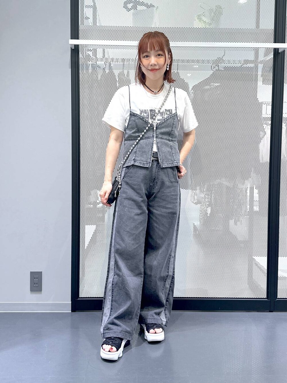 ブラック系のデニムパンツ、グレー系のベスト、ホワイト系のTシャツ/カットソーを着用したレディースの夏コーディネートの3枚目の写真