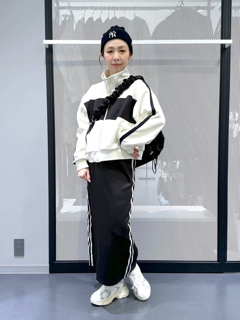 ブラック系のスカート、ベージュ系のブルゾン、ホワイト系のスニーカーを着用したレディースの冬コーディネートの7枚目の写真