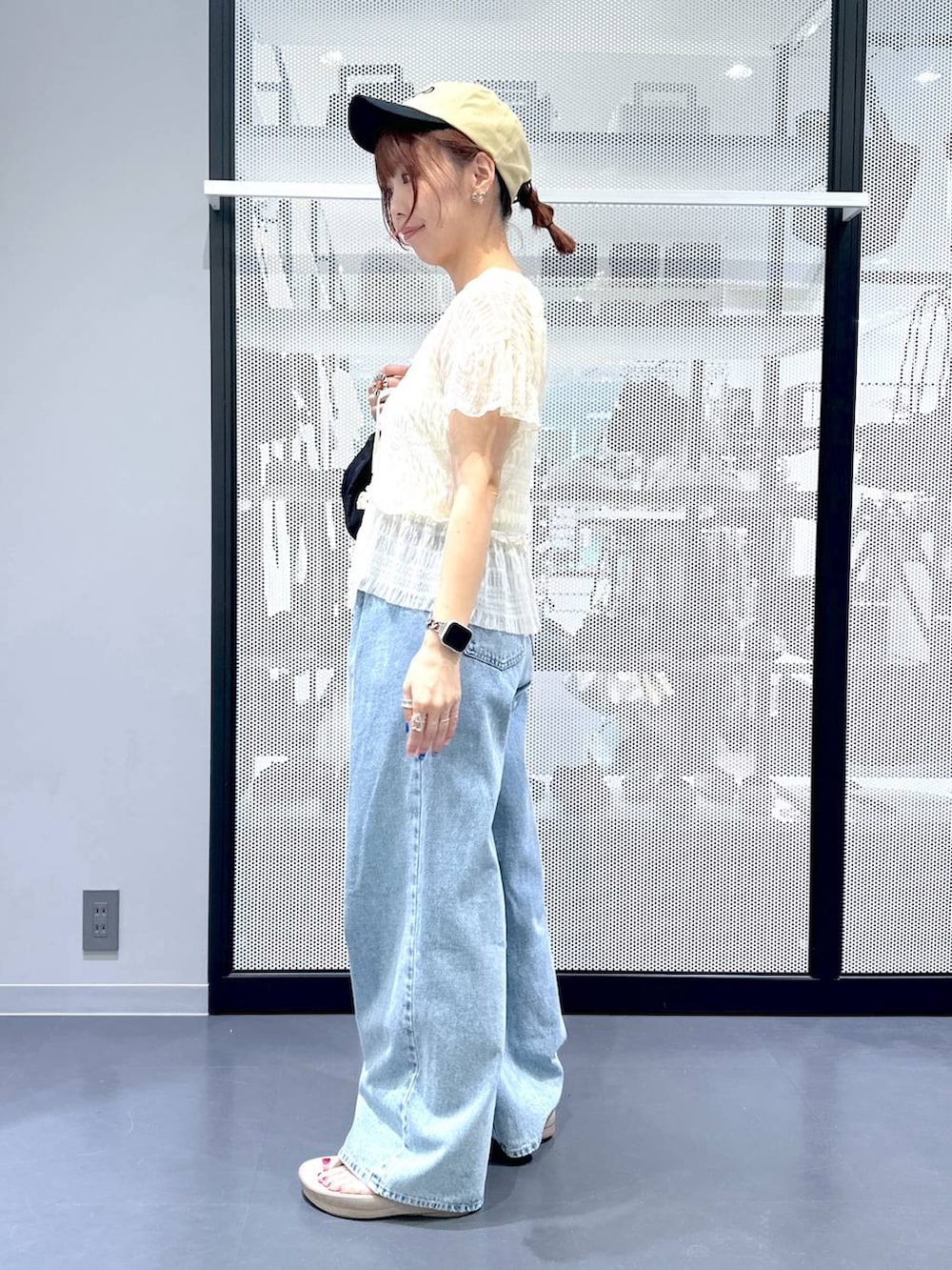 ブルー系のデニムパンツ、ブラック系のハンドバッグ、ベージュ系のサンダルを着用したレディースの夏コーディネートの3枚目の写真
