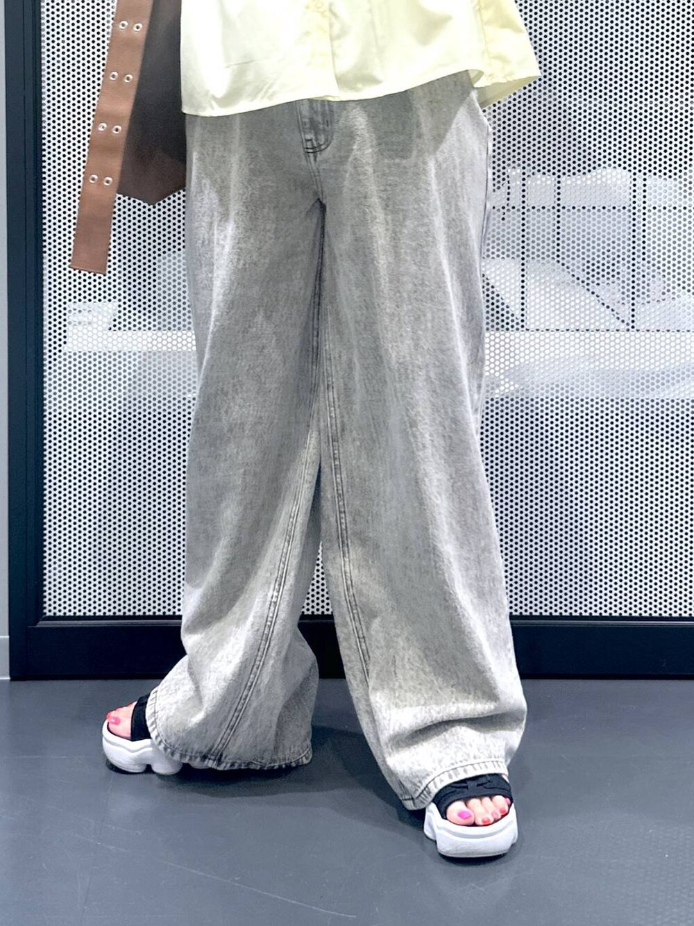 グレー系のデニムパンツ、ブラウン系のショルダーバッグ、イエロー系のシャツ/ブラウスを着用したレディースの夏コーディネートの3枚目の写真
