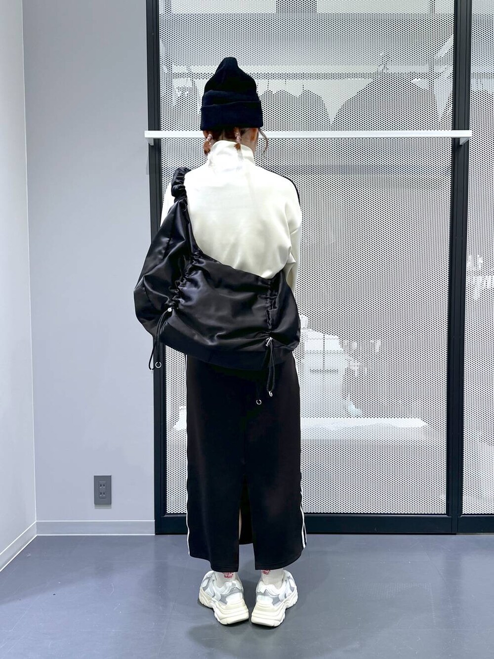 ブラック系のスカート、ベージュ系のブルゾン、ホワイト系のスニーカーを着用したレディースの冬コーディネートの4枚目の写真