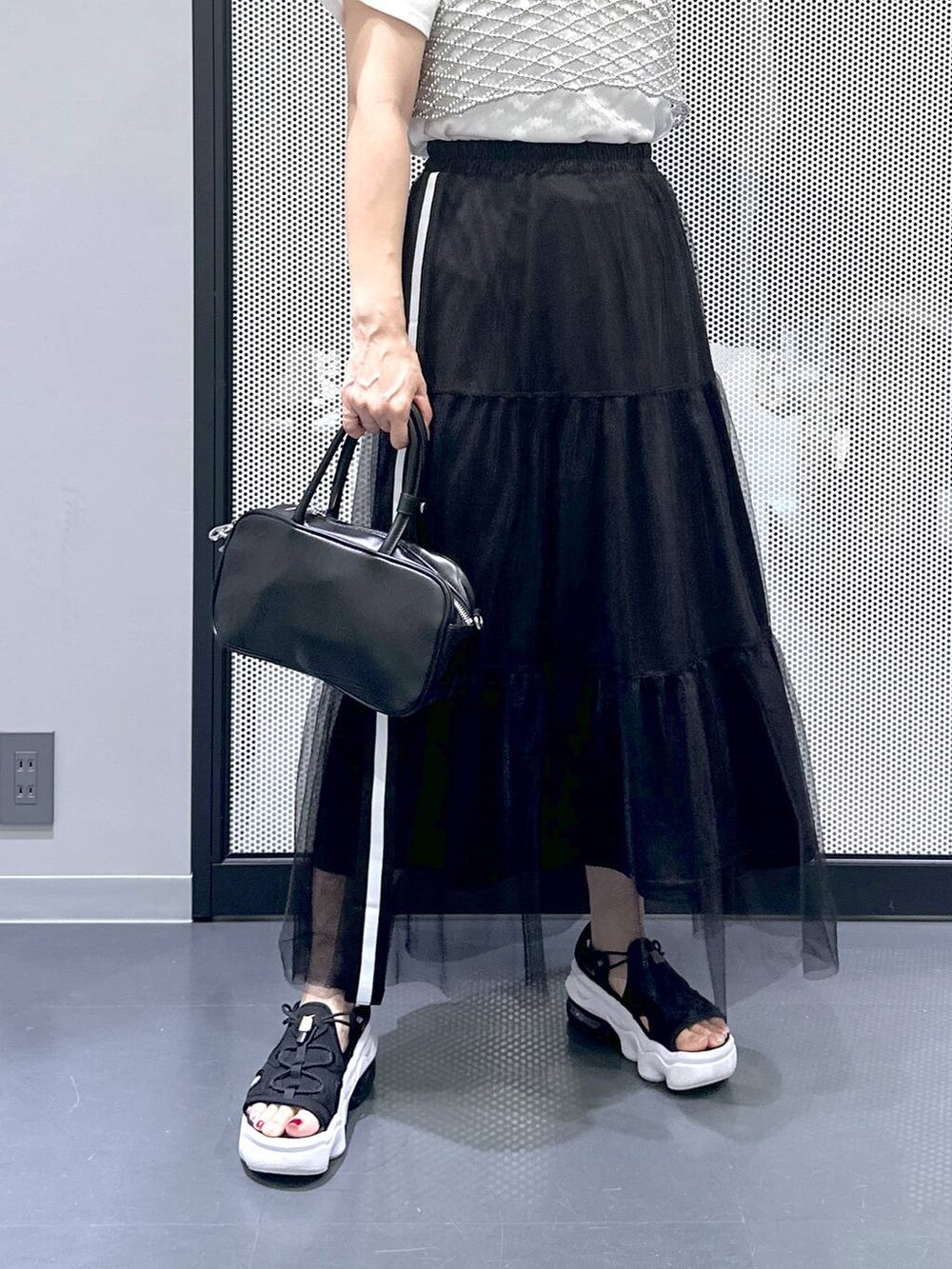 ブラック系のショルダーバッグ、ホワイト系のTシャツ/カットソー、ブラック系のスカートを着用したレディースの夏コーディネートの5枚目の写真