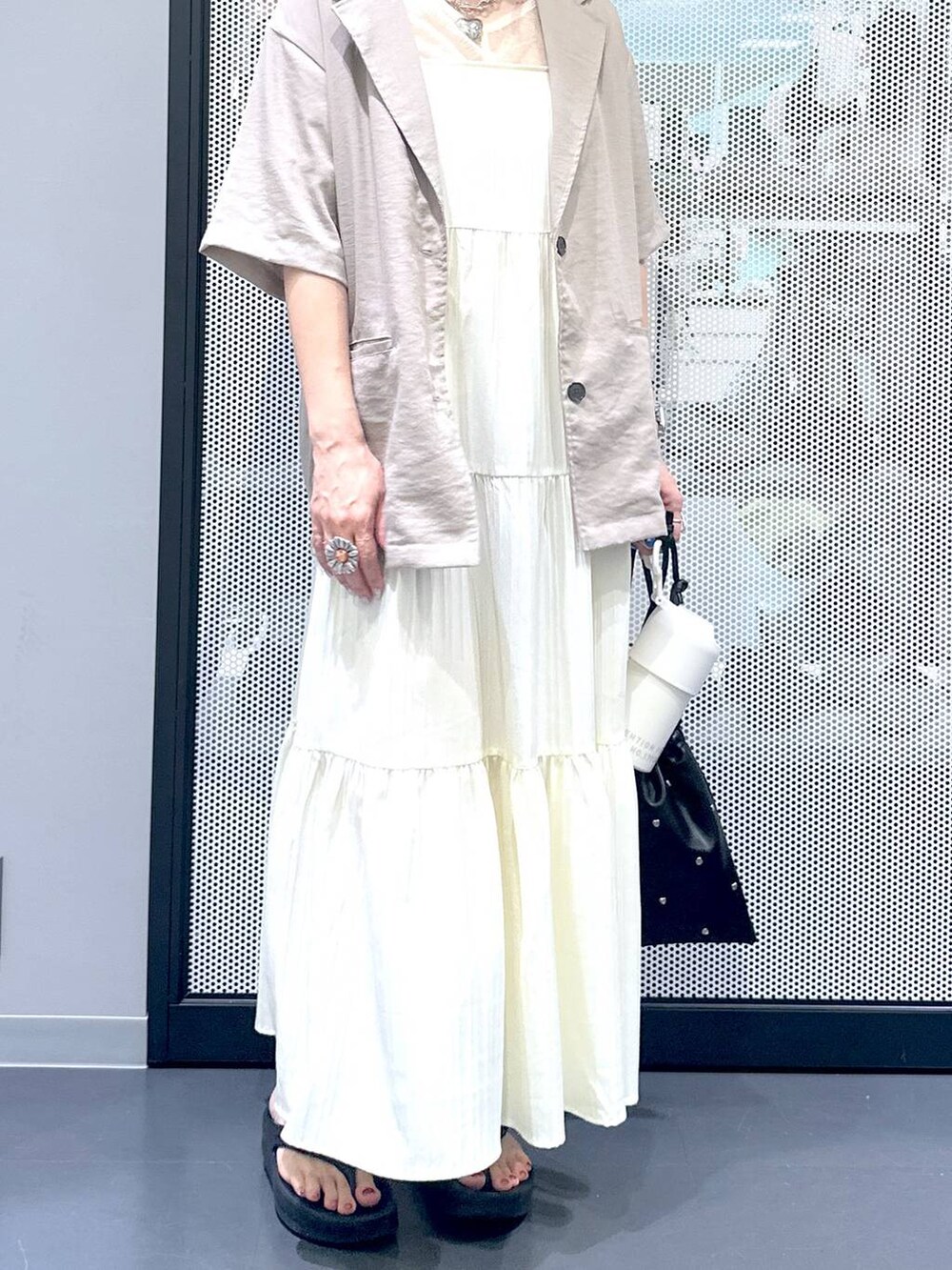 ブラック系のショルダーバッグ、ベージュ系のワンピース、ベージュ系のTシャツ/カットソーを着用したレディースの夏コーディネートの6枚目の写真
