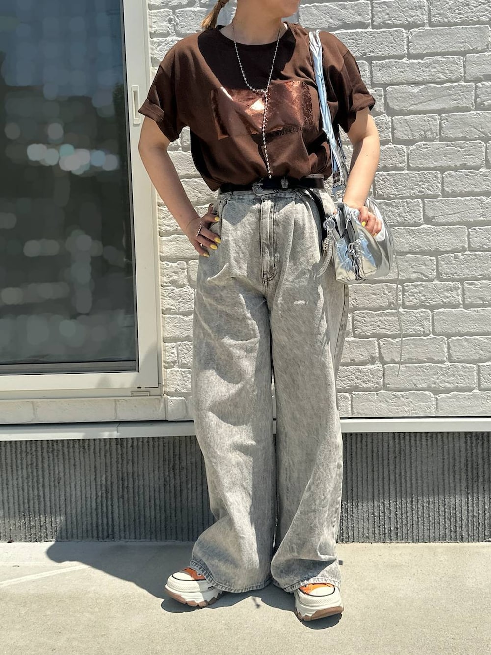 グレー系のデニムパンツ、ブラウン系のTシャツ/カットソー、オレンジ系のスニーカーを着用したレディースの春コーディネートの2枚目の写真