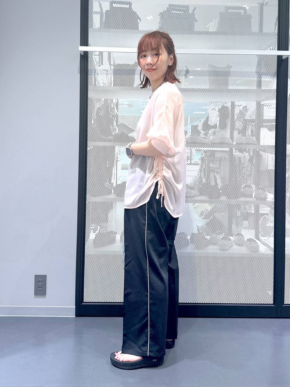 シルバー系のショルダーバッグ、ブラック系のスラックス、ブラック系のサンダルを着用したレディースの夏コーディネートの3枚目の写真