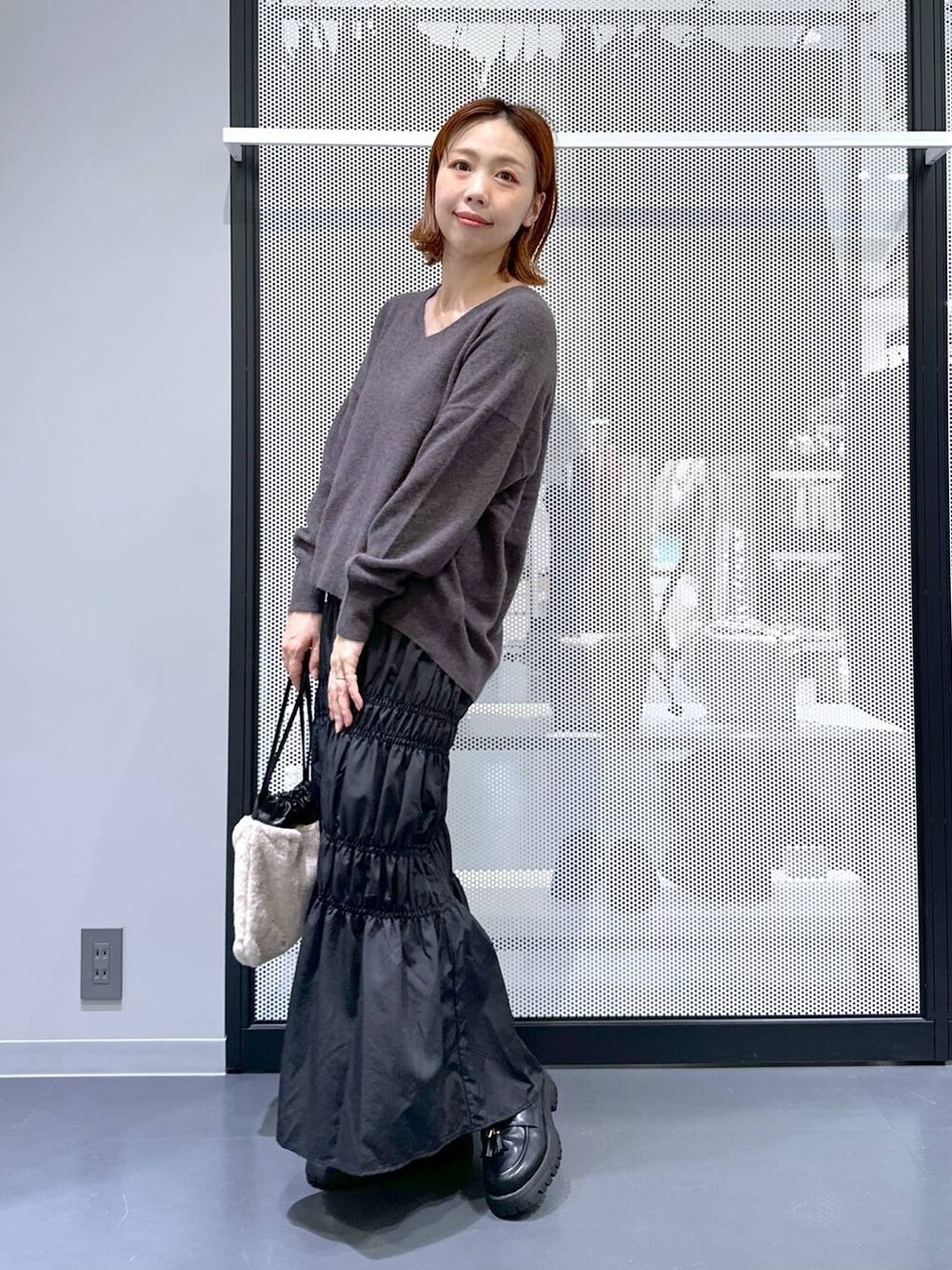 グレー系のニット/セーター、ブラック系のナイロンジャケット、ベージュ系のショルダーバッグを着用したレディースの冬コーディネートの2枚目の写真