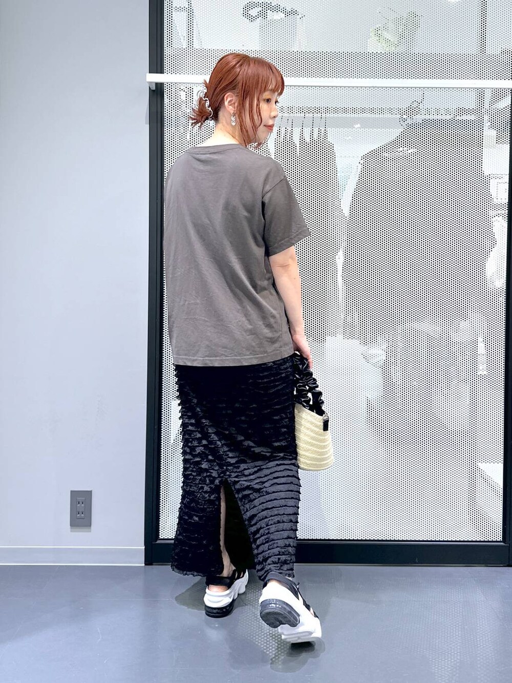 グレー系のTシャツ/カットソー、ブラック系のスカート、ホワイト系のショルダーバッグを着用したレディースの夏コーディネートの3枚目の写真