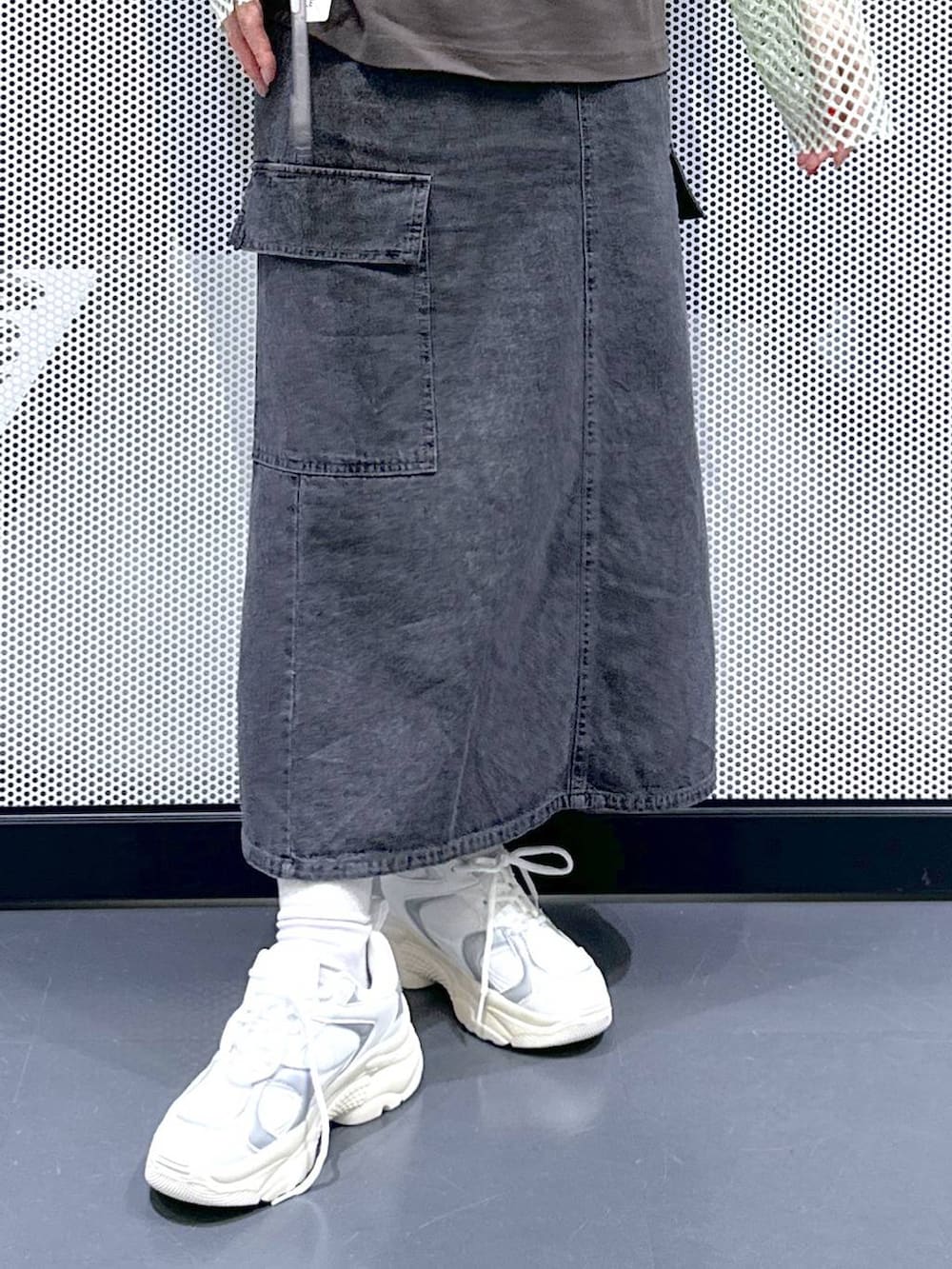 グレー系のデニムスカート、グリーン系のTシャツ/カットソー、ホワイト系のスニーカーを着用したレディースの春コーディネートの6枚目の写真