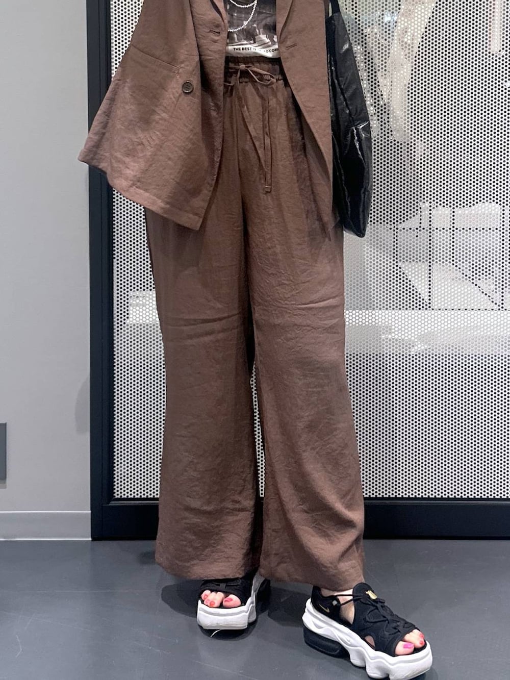 ブラック系のトートバッグ、ブラウン系のテーラードジャケット、ブラウン系のその他パンツを着用したレディースの春コーディネートの5枚目の写真