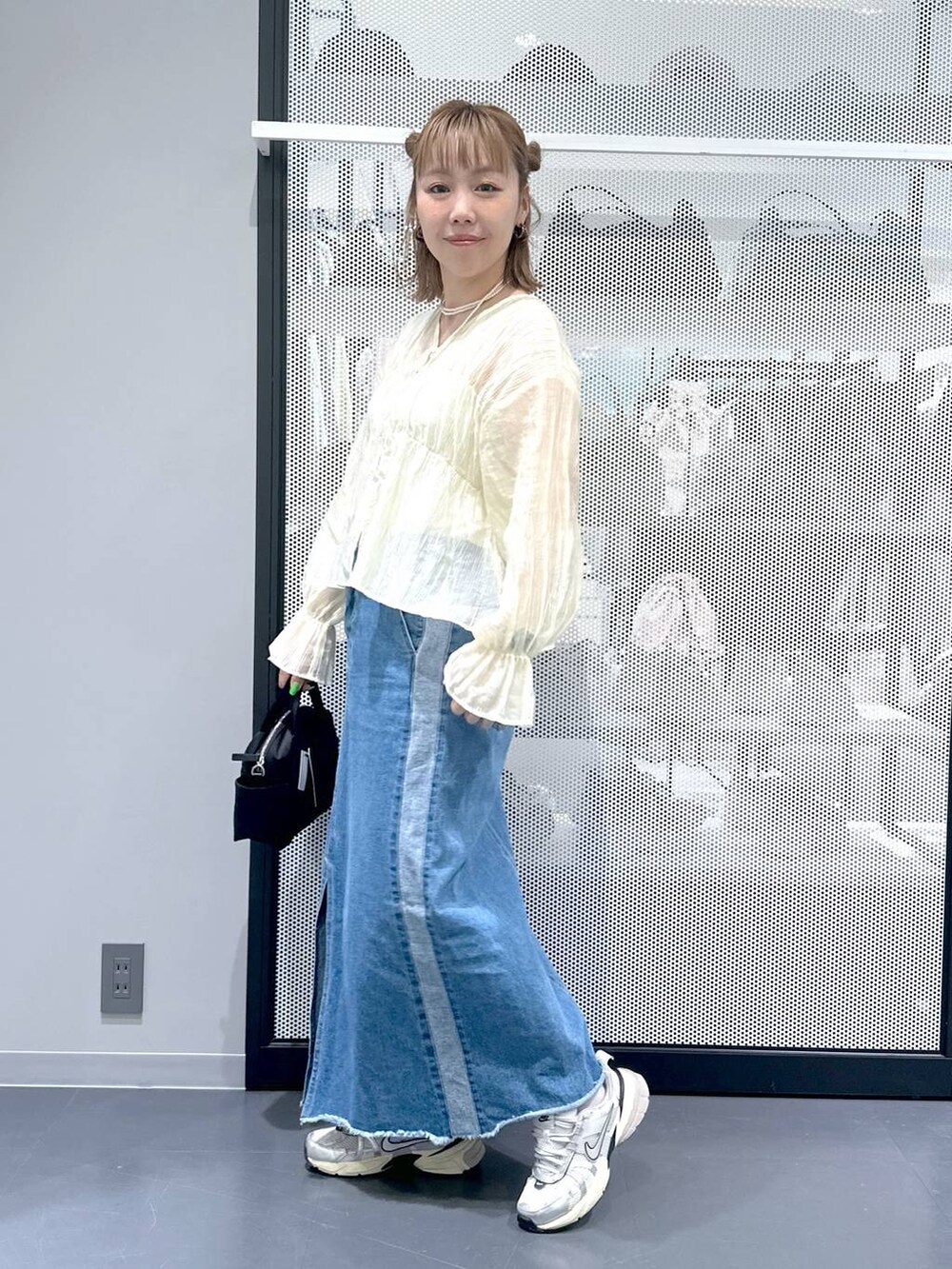 ブルー系のデニムスカート、ベージュ系のシャツ/ブラウス、ブラック系のショルダーバッグを着用したレディースの春コーディネートの2枚目の写真