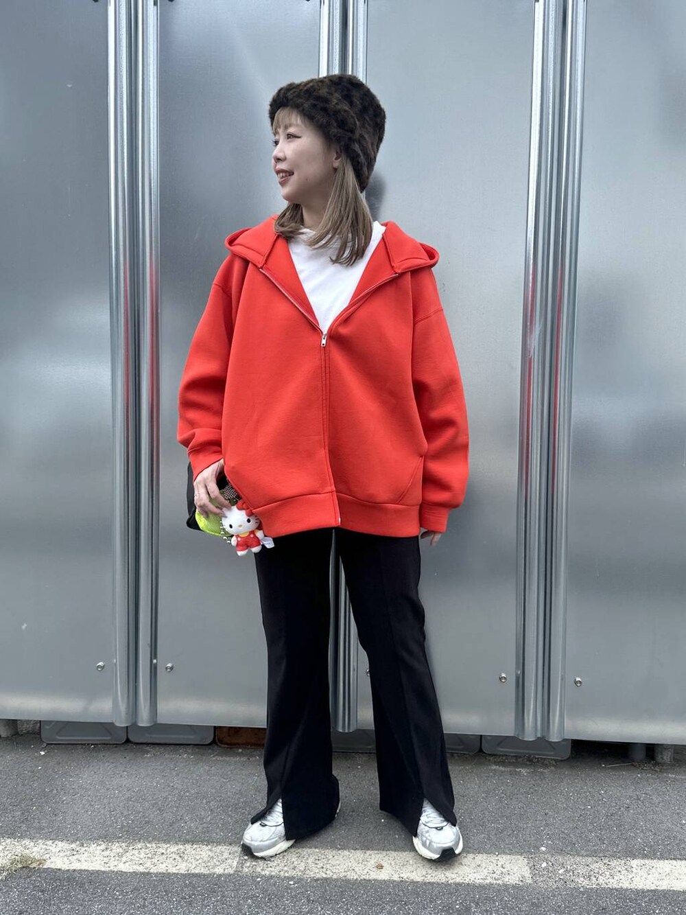 ブラック系のショルダーバッグ、レッド系のパーカー、ブラック系のその他パンツを着用したレディースの秋コーディネートの2枚目の写真