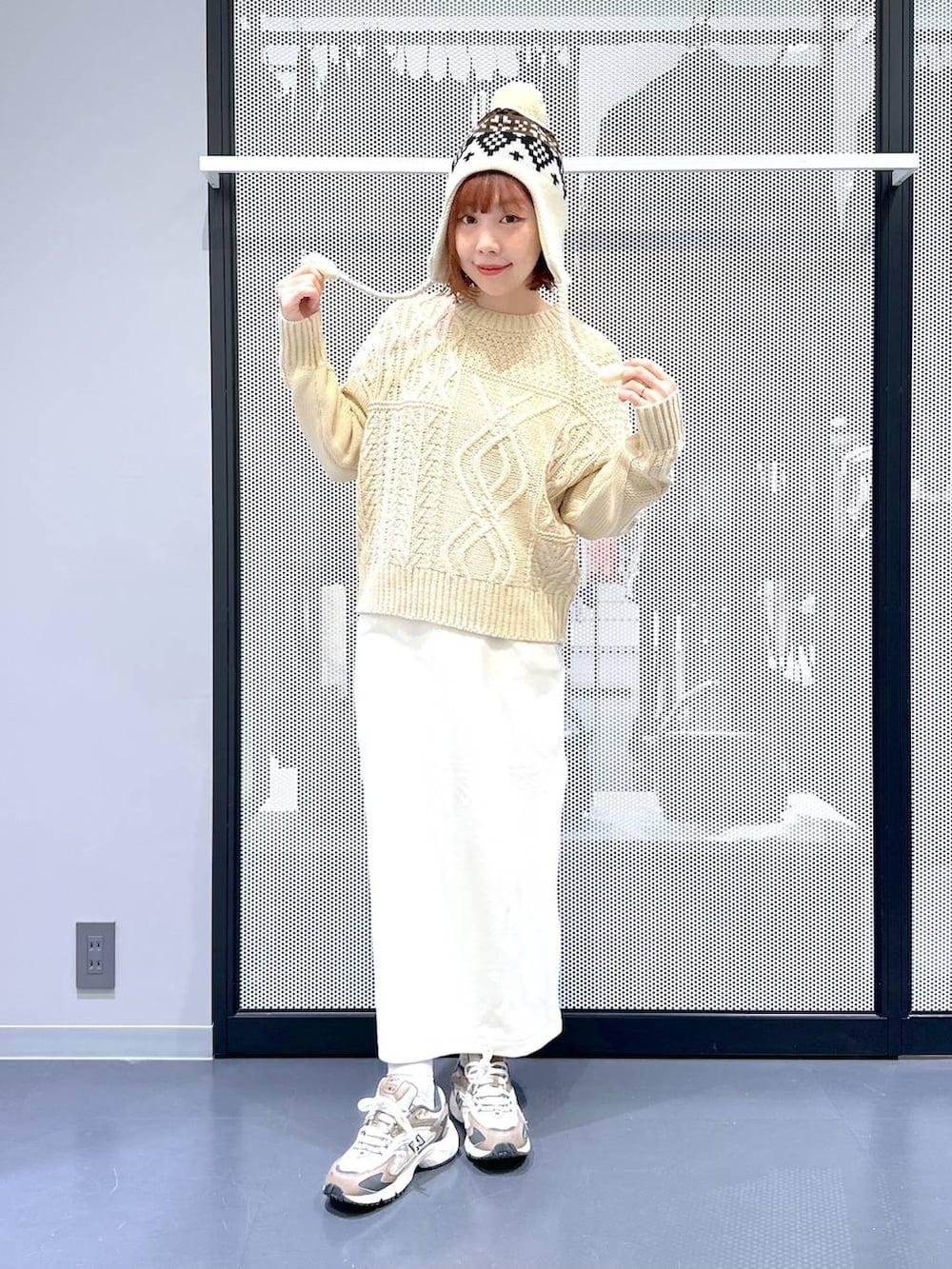 ブラウン系のスニーカー、ベージュ系のショルダーバッグ、グリーン系のナイロンジャケットを着用したレディースの冬コーディネートの2枚目の写真