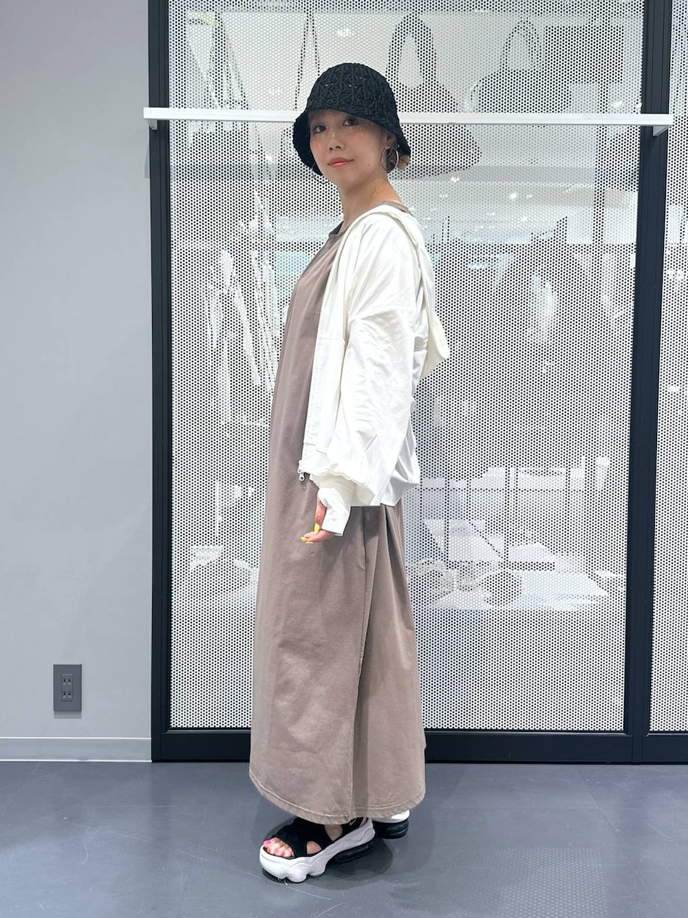 ブラウン系のワンピース、ブラック系のサンダル、ベージュ系の長傘を着用したレディースの春コーディネートの2枚目の写真